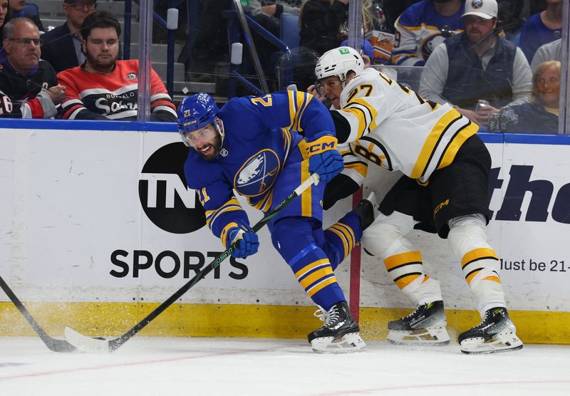 Buffalo Sabres defenseman Conor Timmins plays the puck as Boston Bruins defenseman Hampus Lindholm defends during the third period in game five of the first round of the 2026 Stanley Cup Playoffs at KeyBank Center.