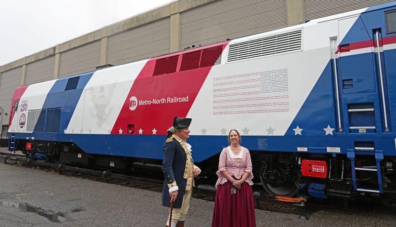 Michael Grillo as George Washington and Cynthia Abbott Kauffman as Ann Fisher Miller, re-enactors from Revolutionary Westchester 250, attended Metro-North's unveiling of a new locomotive for America's 250th anniversary April 30, 2026 at the North White Plains rail facility. This is the ninth locomotive in the Metro-North heritage fleet series.