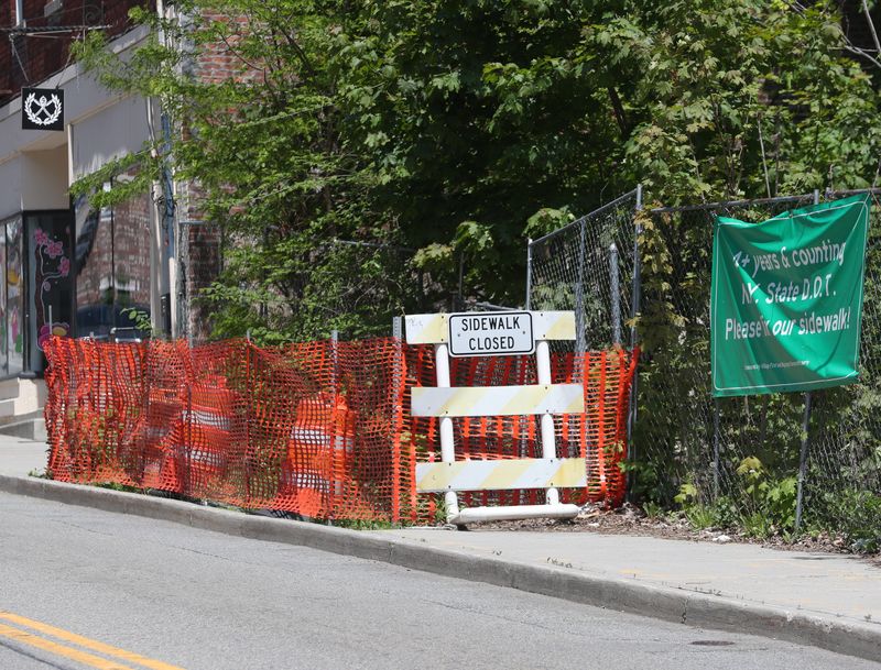 A sign asking the NYS DOT to repair a section of sidewalk on West Main Street in the Village of Wappingers Falls that has been closed since 2020.