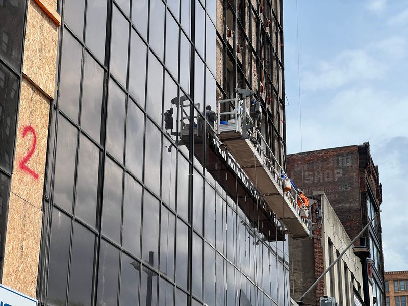 Workers remove the glass curtain wall on the former CGI Communications building on East Main Street in Rochester on May 5, 2026.