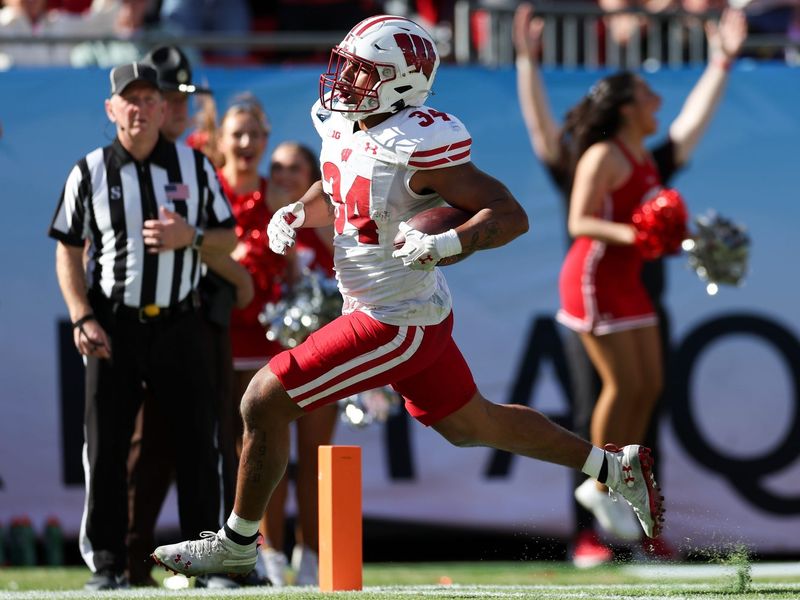 Jan 1, 2024; Tampa, FL, USA; Wisconsin Badgers running back Jackson Acker (34) scores a touchdown against the LSU Tigers in the third quarter during the ReliaQuest Bowl at Raymond James Stadium. Mandatory Credit: Nathan Ray Seebeck-USA TODAY Sports