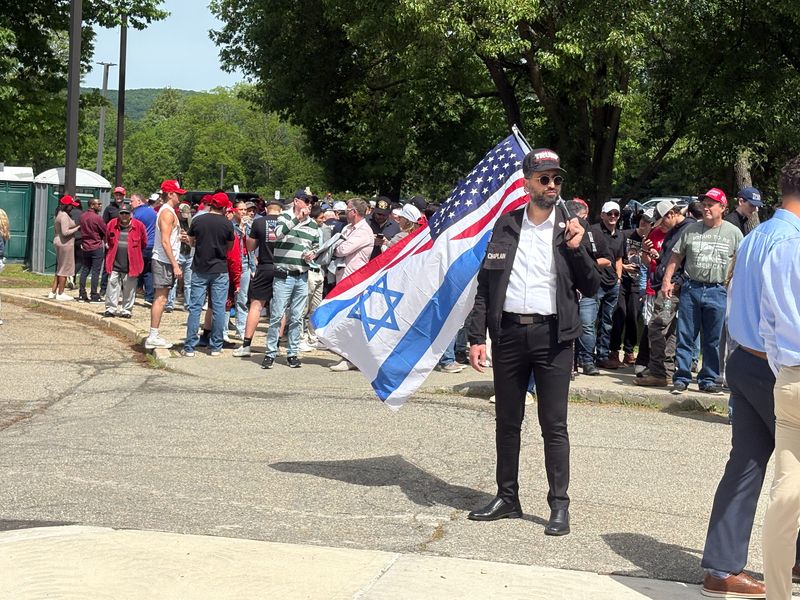 A Trump supporter holding an Israeli-American flag stands in line outside Rockland County Community College on Friday, May 22, 2026, ahead of a visit to the school by President Donald Trump.