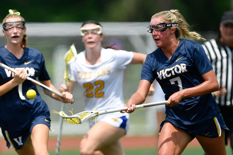 Victor's Lila Kubrich, right, reaches for a loose ball during a NYSPHSAA Girls Lacrosse Championships Class B semifinal Friday, June 12, 2026, in Cortland, N.Y. Victor advanced to the finals with a 17-8 win over Queensbury (II).
