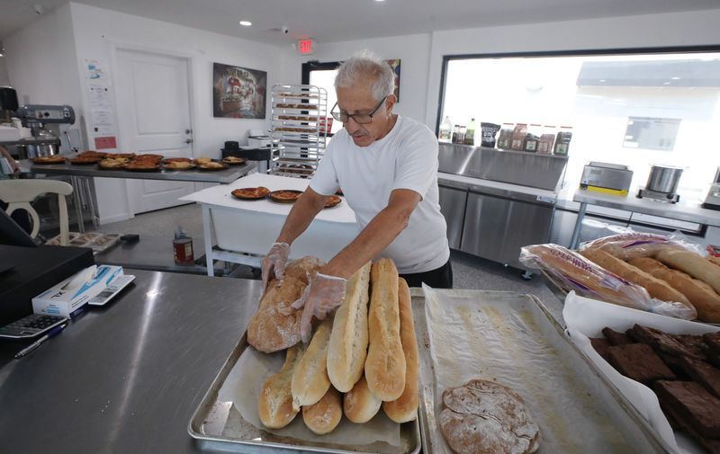 Frank Martusciello organizes a variety of loaves of fresh bread on the counter at his newly opened Casa Saratoga bakery on Spencerport Road in Gates Monday, July 13, 2026.