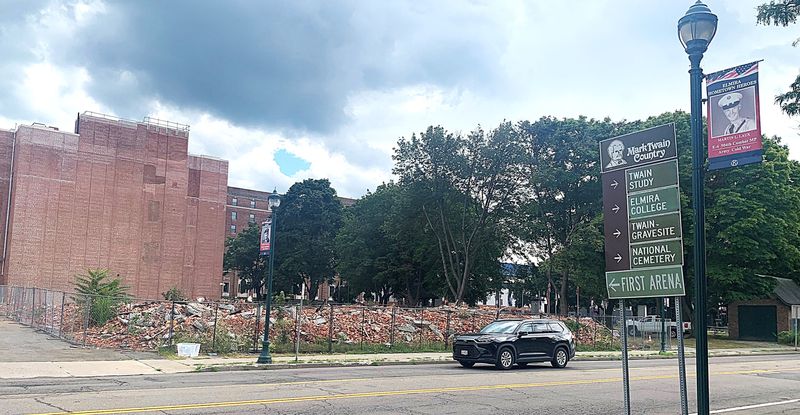 A pile of fenced-in rubble still sits on the site of a former Baptist church in downtown Elmira that was gutted by flames in February 2025. Chemung County has foreclosed on the property for back taxes.