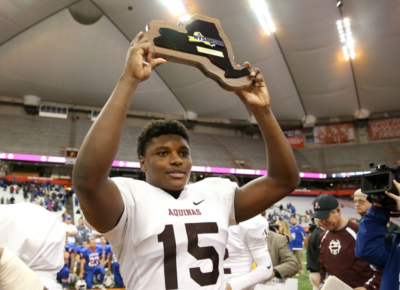 Aquinas' Jamir Jones holds up the NYSPHSAA championship plaque after the Lil Irish defeated Saratoga Springs in the Class AA state final Nov. 29, 2015.