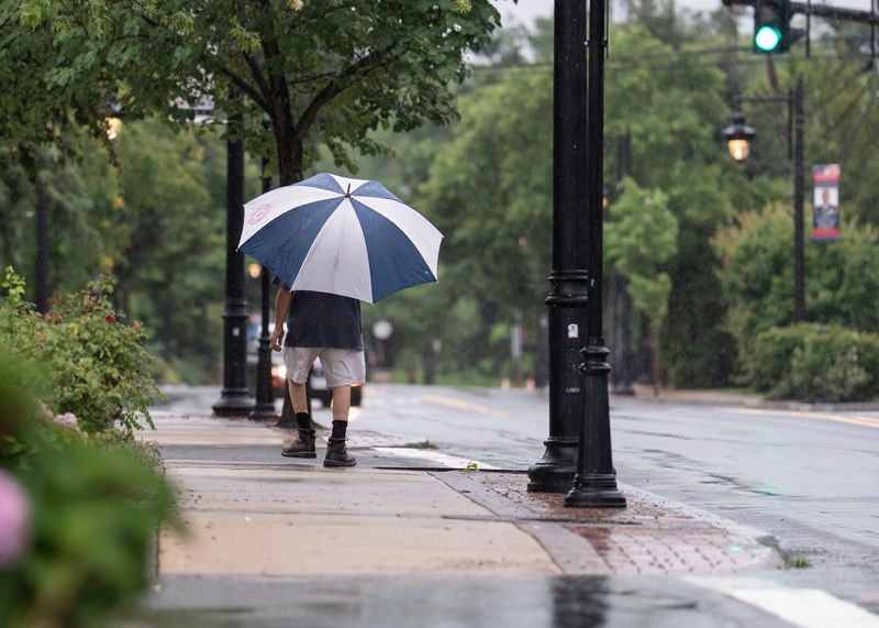 A pedestrian walks with an umbrella along Main Street in New City on Tuesday, July 21, 2026.