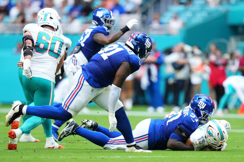 Aug 22, 2026; Miami Gardens, Florida, USA;  New York Giants defensive lineman Bobby Jamison-Travis (97) tackles Miami Dolphins quarterback Cam Miller (15) during the first quarter of a preseason game at Hard Rock Stadium.  Mandatory Credit: Rich Storry-Imagn Images