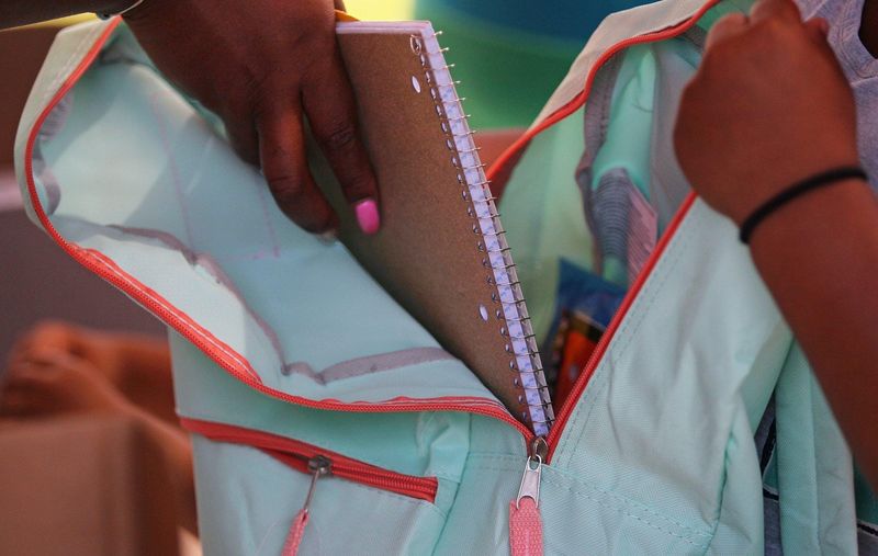 A volunteer places school supplies in a child's backpack during the second annual BackPack 2 School event at Lock 3 Park, Sunday, Aug. 4, 2019 in Akron, Ohio.