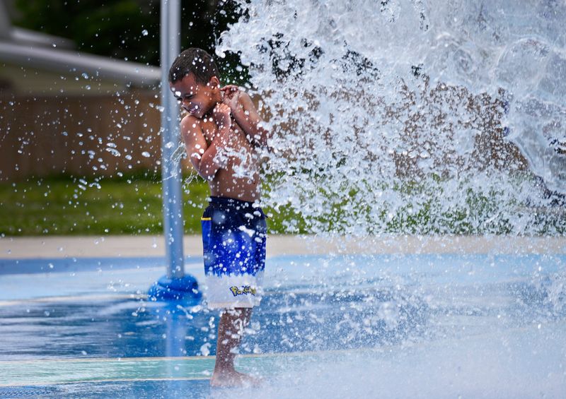 Isaiah Williams, 6, of Blue Ash, gets soaked as the bucket overhead dump water at the splash pad at Gorman Park in Sharonville, Tuesday, May 30, 2023. The splash pad opened last summer and has become a go-to place for many families. Temperatures are expected to reach into the 90’s this week.