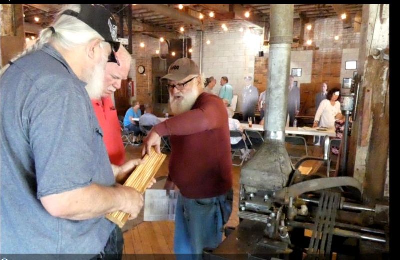 Wayne Clark, left, and Earl Sayre, at right, volunteers at the Shawshank Woodshop and Museum, show a visitor the grooves in the wood made by the shaper machine in the woodshop in Upper Sandusky where scenes from "The Shawshank Redemption" were filmed in 1993.