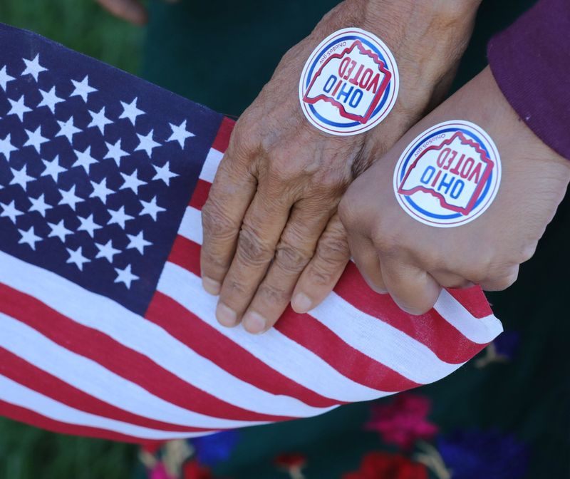 First time voters Redika Lumzel, and Deuki Lumzel, are photographed with the American flag after voting at the Bolich Middle School polling station on Tuesday, Nov. 3, 2020 in Cuyahoga Falls, Ohio. [Phil Masturzo/ Beacon Journal]