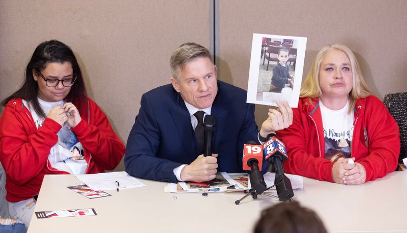 Bobby DiCello with the law firm DiCello Levitt holds a photo of one of Zachary Fornash's children at a news conference in December 2023 at the Stark Community Support Network in Canton. Also at the table are Fornash's wife Alexus Fornash, left, and his mother Cassandra White.