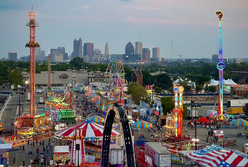 Jul 26, 2024; Columbus, OH, USA; Visitors to the Ohio State Fair enjoy rides on the midway as sun sets on the Columbus skyline.