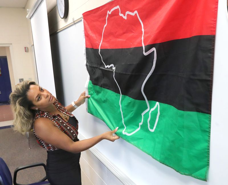Twinsburg High School Black Literature and English teacher Daneé Pinckney hangs a Pan African flag in her classroom on Wednesday, Aug. 7, 2024, in Twinsburg, Ohio
