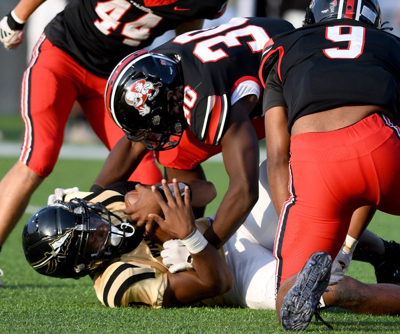 McKinley's Antonio Stevens stands over Warren Harding quarterback Chaz Coleman in the first quarter of Warren Harding at Canton McKinley Football at Tom Benson Hall of Fame Stadium. Thursday, August 22, 2024.