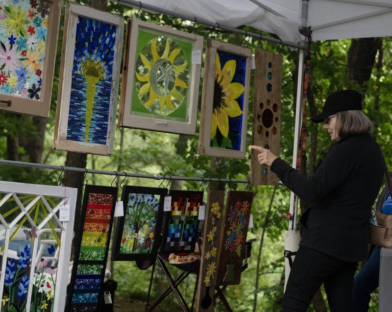 Kathy Harris looks at the repurposed glass mosaic pieces of Sherri Rossi at the 2024 Art in the Park event in Kent. The festival will return to Fred Fuller Park on Sept. 6-7.