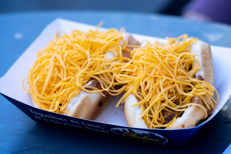 Alex Salatin places Skyline Chili hotdogs on a cooker while Skyline Chili celebrates their anniversary at Fountain Square in Cincinnati on Wednesday, Oct. 9, 2024.