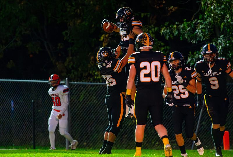 Garfield offensive lineman Michael Huebner (55) lifts running back Ryder Cain (35) into the air after Cain's touchdown during the first quarter of the team's win over Newton Falls.