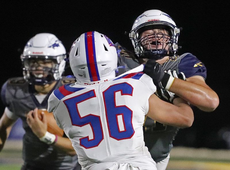 Copley quarterback Gabe Mansel looks to run as Lucas Tielsch blocks Revere defensive lineman Joe Sunkin, Friday Oct. 18, 2024.