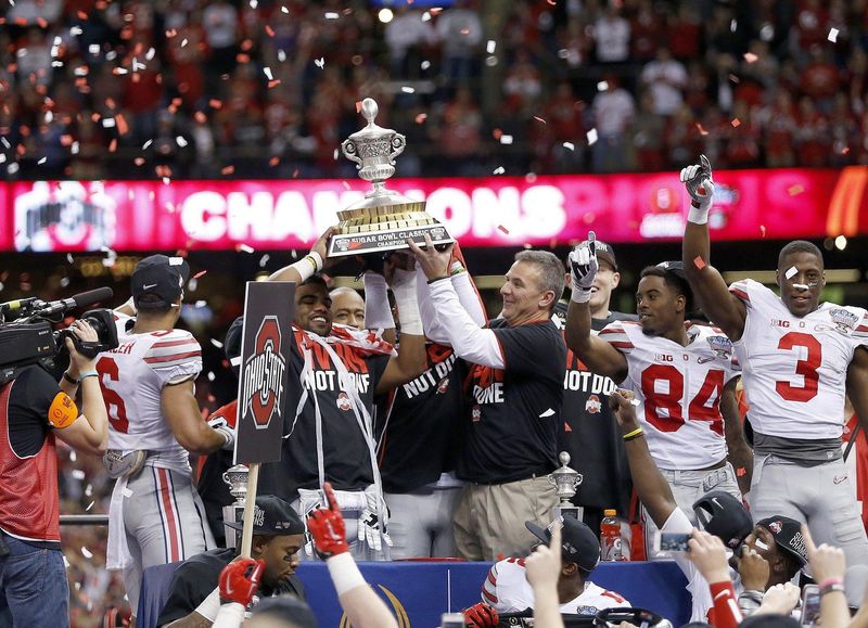 Coach Urban Meyer and running back Ezekiel Elliott hold up the trophy following a College Football Playoff semifinal win over Alabama on Jan. 1, 2015.