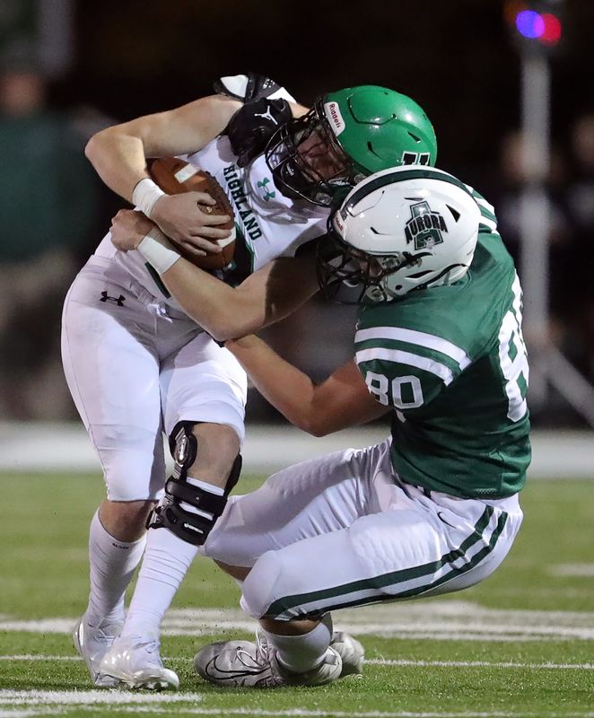 Highland quarterback Dylan Borla, left, is wrapped up by Aurora defensive lineman Luke Bonnette during the second half of a high school football game, Friday, Oct. 25, 2024, in Aurora, Ohio.