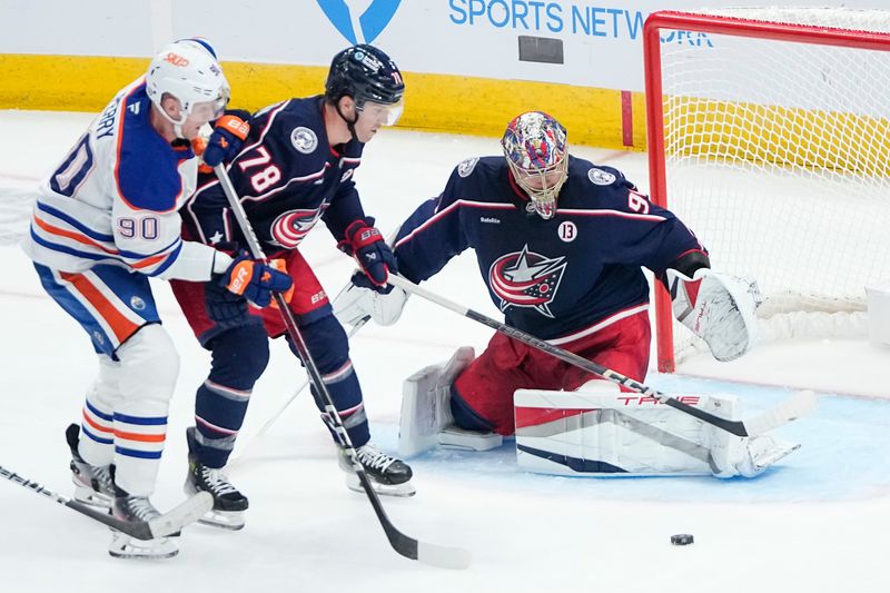 Blue Jackets goaltender Elvis Merzlikins saves a shot in front of defenseman Damon Severson and Edmonton right wing Corey Perry on Oct. 28.