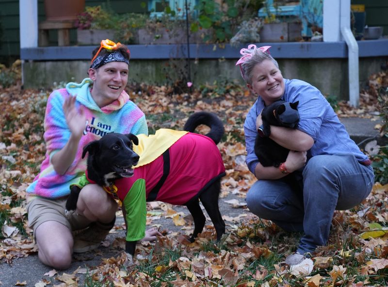 Addison Torrence (left) holds Otis, dressed as Batman, as Johnna Keller cradles Sam, dressed as Robin, as trick-or-treat gets underway in Clintonville Thursday, October 31, 2024, in Columbus.