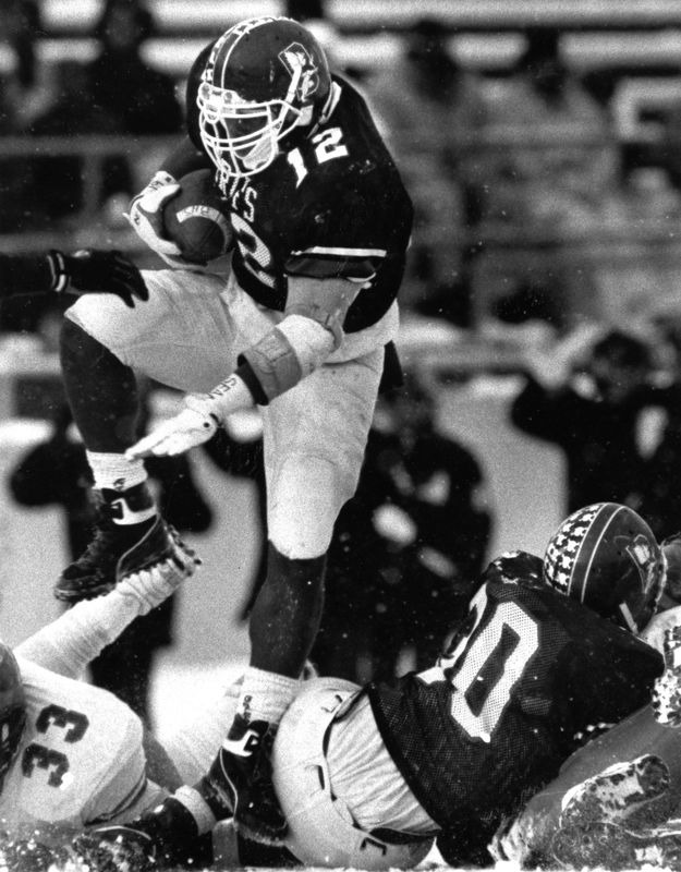 Buchtel High School star Ricky Powers hops through the hole in the City Series Thanksgiving Day Championship against Ellet on Nov. 23, 1989, at the Rubber Bowl. Ellet won 7-6.