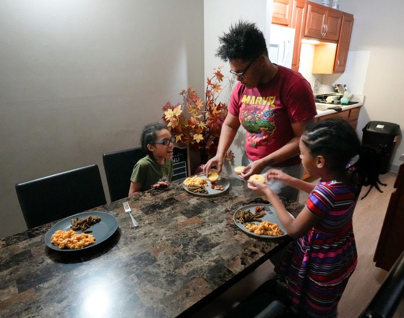 Jontayesha Brown serves up the corn bread to her children Davonte, 8, and Larayah, 6, as the get ready to eat dinner in their Spring Hill apartment on Friday, Jan. 24, 2025 in Akron. Brown made pork chops, canned green beans, mac and cheese and corn bread for dinner.