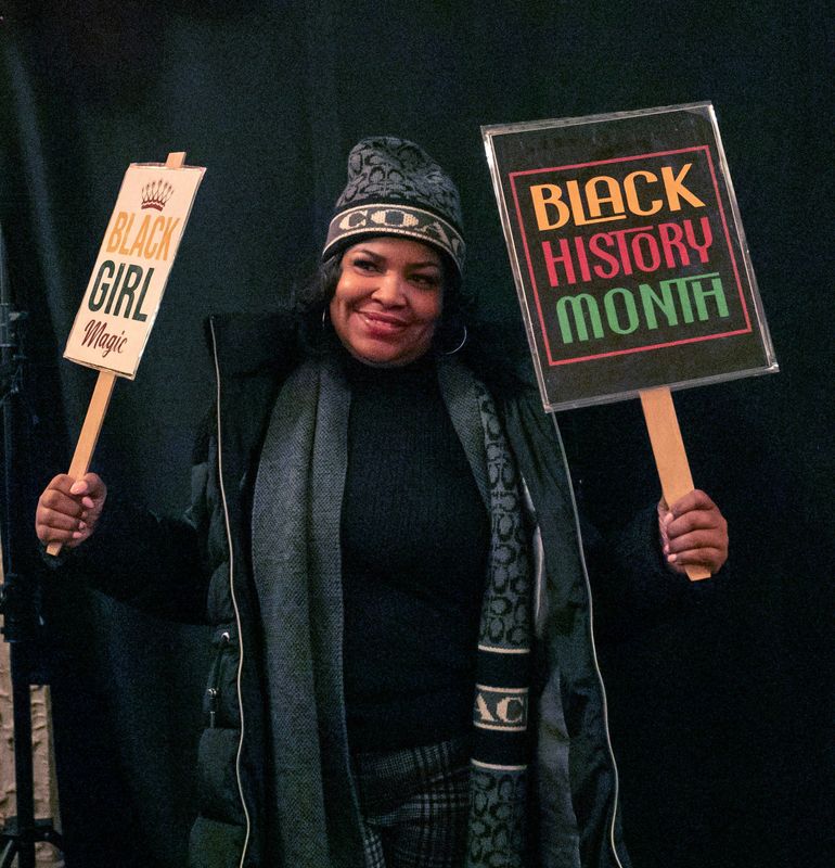 April Leak, of Milwaukee, Wis., holds up signs in the lobby before the Black History Celebration at the Stefanie H. Weill Center for the Performing Arts, Saturday, February 15, 2025, in Sheboygan, Wis.