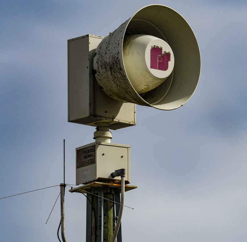 A tornado siren stands next to storm damage as emergency crews re-route traffic after severe weather passed through the Eagle Creek area near the intersection of Lafayette Road and Traders lane on Thursday, April 3, 2025, in Indianapolis.