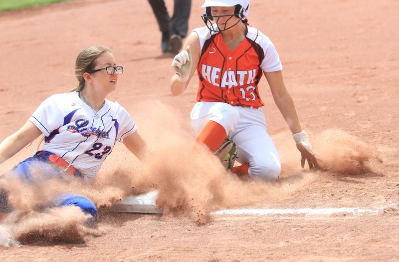 Heath's Kyndall Spicer slides safely into third base ahead of the tag of Lakewood's Briana Hoisington during the visiting Bulldogs' 8-7 victory in a Division IV second-round game on May 17, 2025.