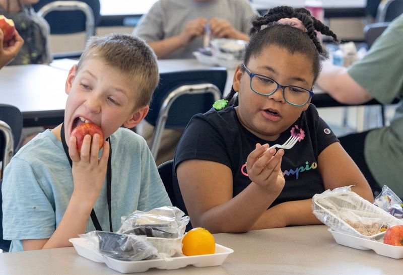 Noah Leech, 8, and Alainna Burgen, 8, eat lunch at the Alliance Summer Explorers Program at Alliance Middle School. Alliance City Schools is one of many sites offering free meals for children 18 and younger this summer.