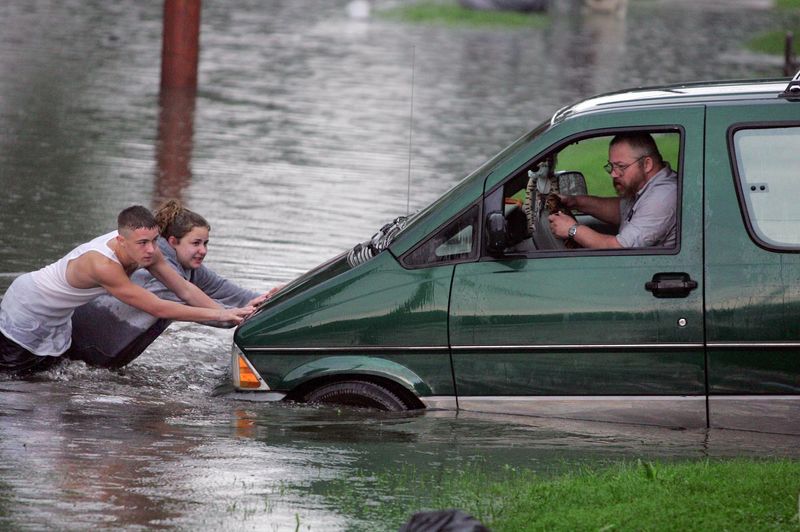 Ricky Quinn 15, Heather Brown 20, push the family Ford Aerostar van from the flooded 16th Street N.W. water on Monday, Aug. 20, 2007, in Barberton, Ohio. Richard Quinn steers into the driveway. (Phil Masturzo/Akron Beacon Journal)