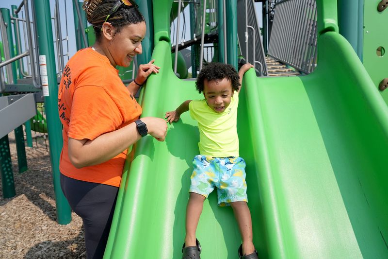 Jazmin Elder helps son Legend Brown on the slide at Weis Park in Canton.