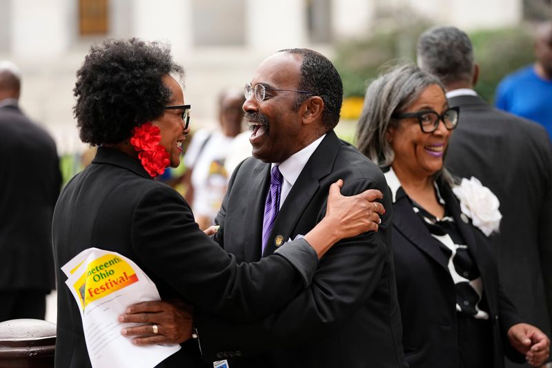 Sen. Hearcel Craig hugs State Rep. Meredith Lawson-Rowe after raising the Juneteenth flag in front of the Ohio Statehouse in Columbus on June 18, 2025.