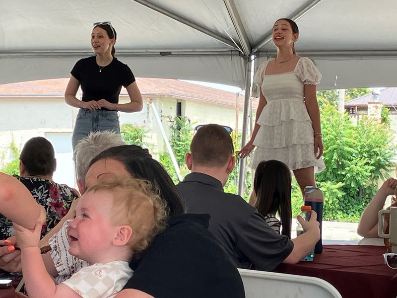 Taylor and Morgyn Beasley, from Lexington, sing a number at Friday's lunch to recognize fundraising efforts for a new building for the Mansfield Playhouse as a baby smiles in the foreground.