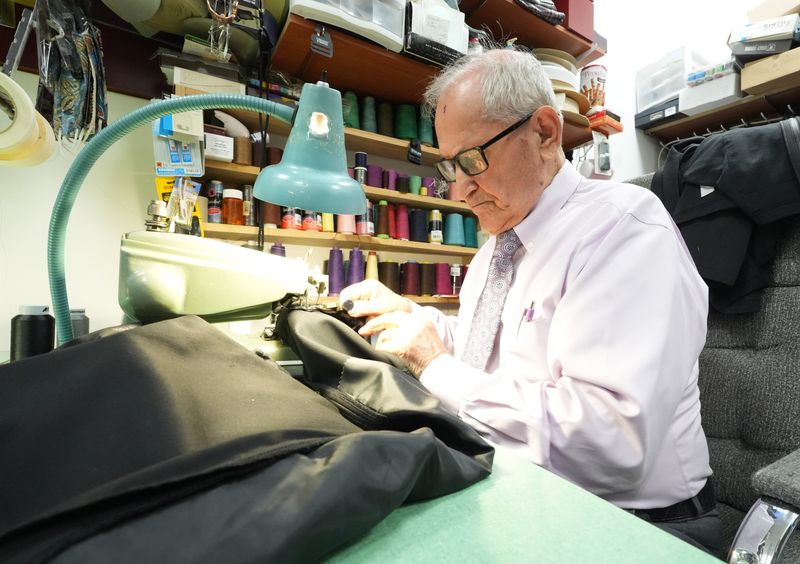 George Tsaftarides, owner of George's Menswear & Tailoring in Jackson Township, hems a pair of pants at the business. Tsaftarides, 84, is also a popular social media personality.