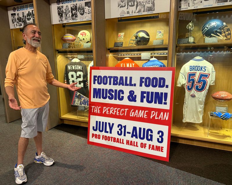 Vicente Aguilar, 61, of Sherman, Texas, checks out one of the exhibits at the Pro Football Hall of Fame in July. A sign also advertises the new Fan Fest from July 31 to Aug. 3 during the Pro Football Hall of Fame Enshrinement Festival.