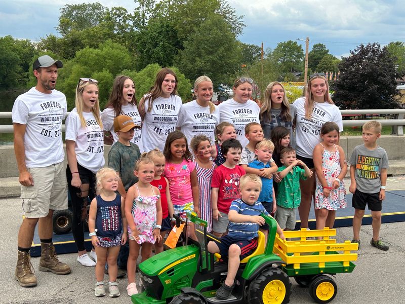 Woodmore FFA Advisor Ryan Avers stands with FFA members and kiddie tractor pull participants.