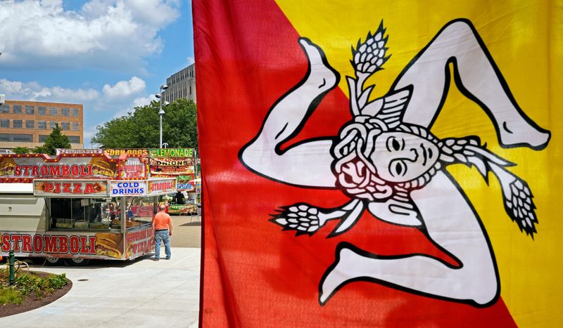 A festival goer is framed by the Sicilian flag as he orders food at Lock 3 during the Summit County Italian American Festival, Saturday, July 12, 2025, in Akron, Ohio.