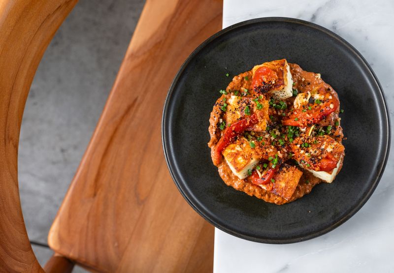 Seared halloumi at Comune is served with roasted sweet peppers and a thick sauce made from them, preserved lemon and chives.