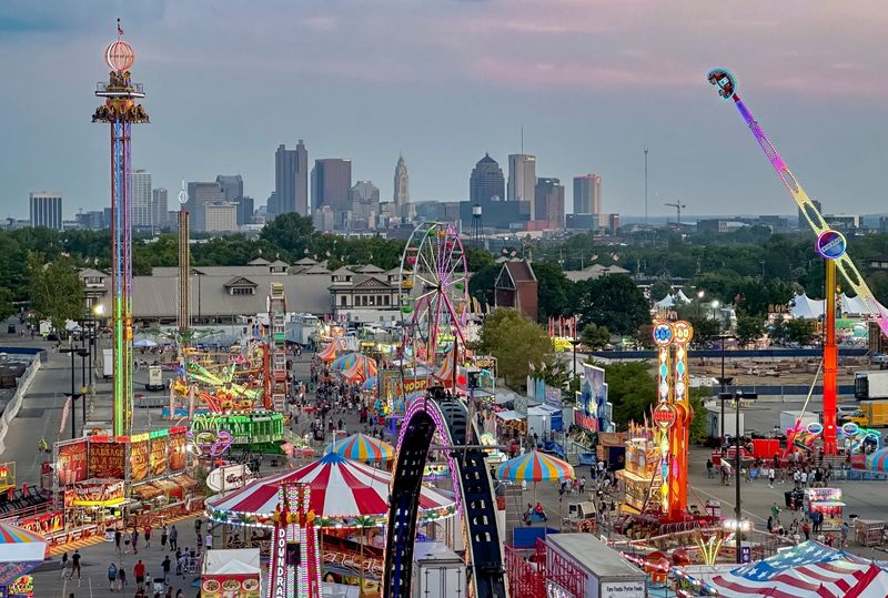 Visitors to the Ohio State Fair on enjoy rides on the midway as sun sets on the Columbus skyline.