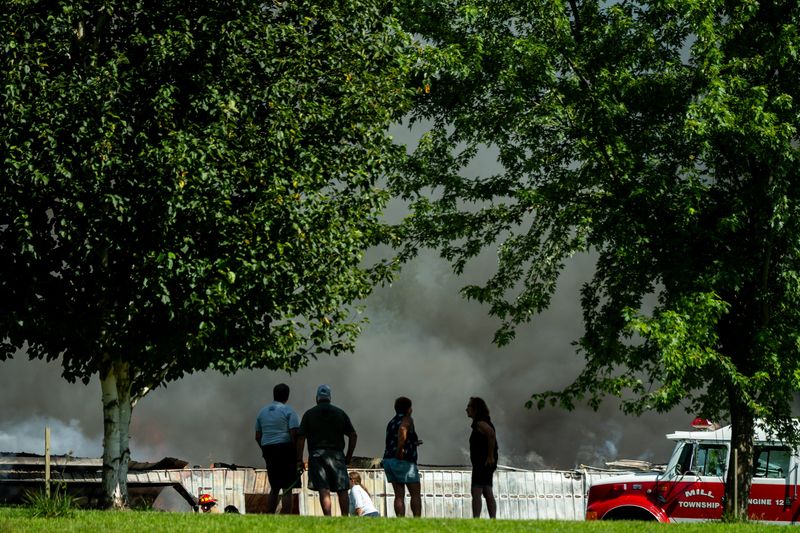 People at 1719 Roxford Church Rd SE watch firefighter battle a pole barn fire, July 22, 2025, in Union Township, OH.