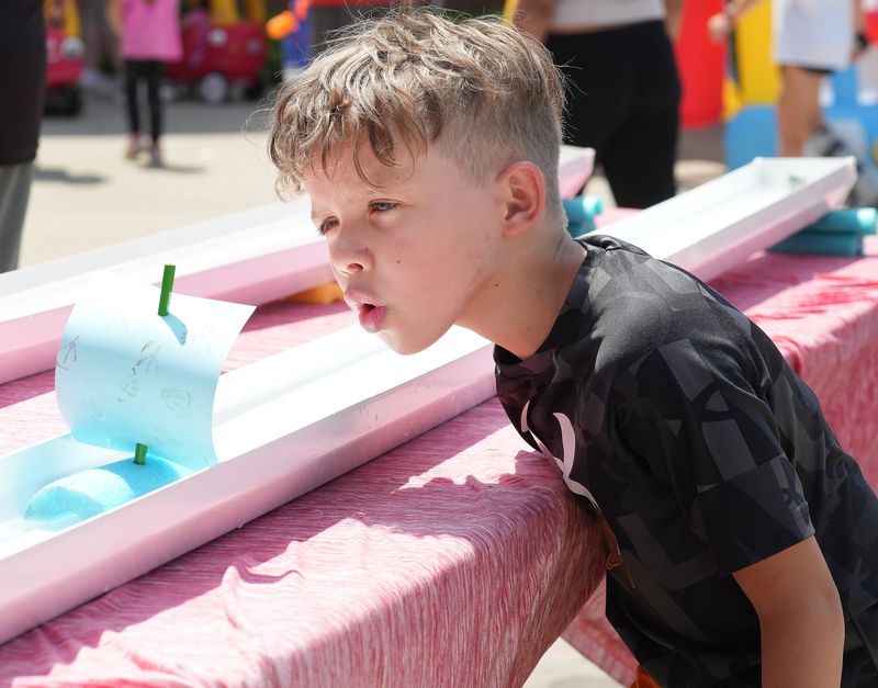 Jayvion Brothers, 6, blows his ship's sail in the Rain Gutter Regatta sponsored by the Cub Scouts at the Massillon Fun Fest downtown.