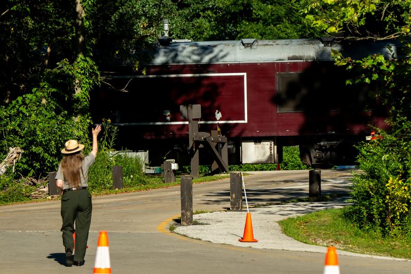 A National Park Service Ranger at the Cuyahoga Valley National Park waves to an arriving train of dignitaries during a tour of the completed Cuyahoga River riverbank stabilization project, made possible by the Great American Outdoors Act Legacy Restoration fund, Aug. 18, 2025, at the Lock 29 Trailhead in Peninsula, Ohio.