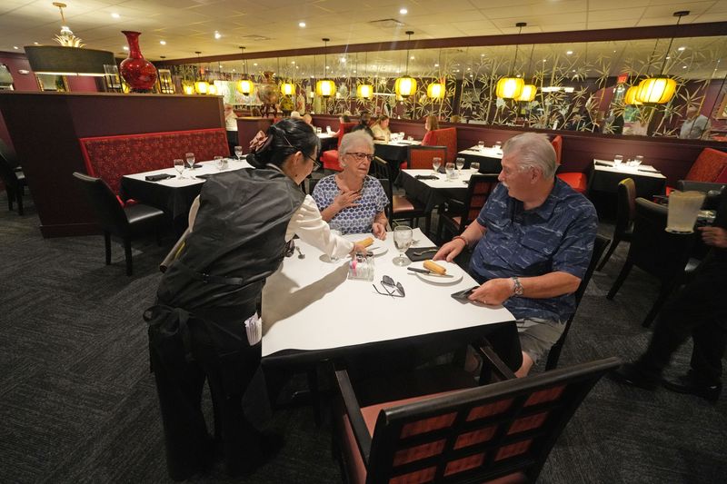 Hunan Lion server Yee Li serves dinner to Kathleen and Thomas Hess. Nearly two years after a fire that destroyed its kitchen equipment, Hunan Lion reopened Tuesday, August 19, 2025.