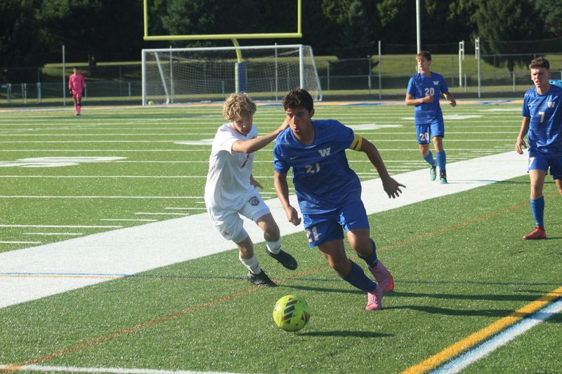 Wooster midfielder Calen Relle dribbles near the touchline.
