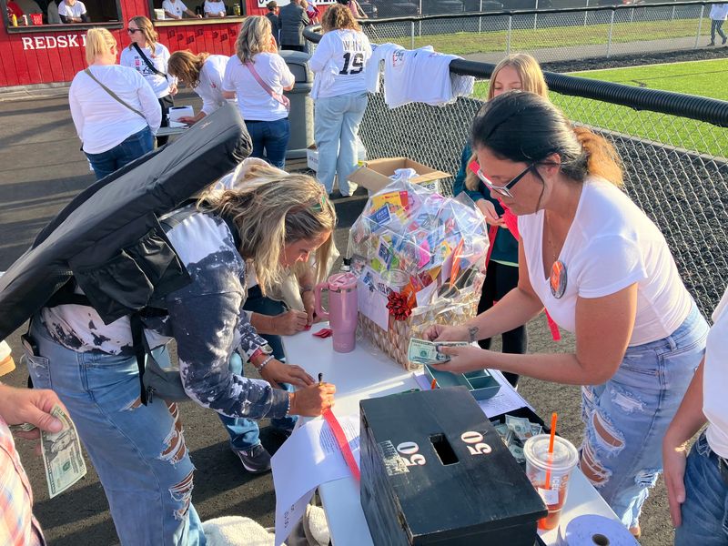 A fan pays for a raffle on a gift basket to benefit the family of Tuscarawas Valley freshman Mayson White before the Trojans' high school football game on Friday, Aug. 30, 2025, at Stewart Field in Coshocton. The raffle, organized by Coshocton football parent Ashley Shearn, featured more than 40 donated items from local businesses and individuals around Coshocton. White was paralyzed after a collision during TV's Week 1 game against Apple Creek Waynedale.